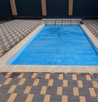 Прямоугольный композитный бассейн с синим покрывалом и каменным бортиком